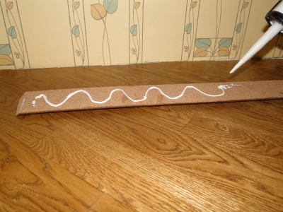 Нанесение фиксирующего клея на плинтус