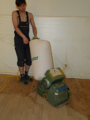 Мастер проводит циклевку паркета